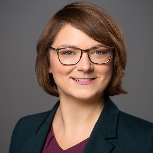 Portrait von Susanne Possinger mit halblangem und gescheitelten braunen Haaren. Sie trägt eine Brille.